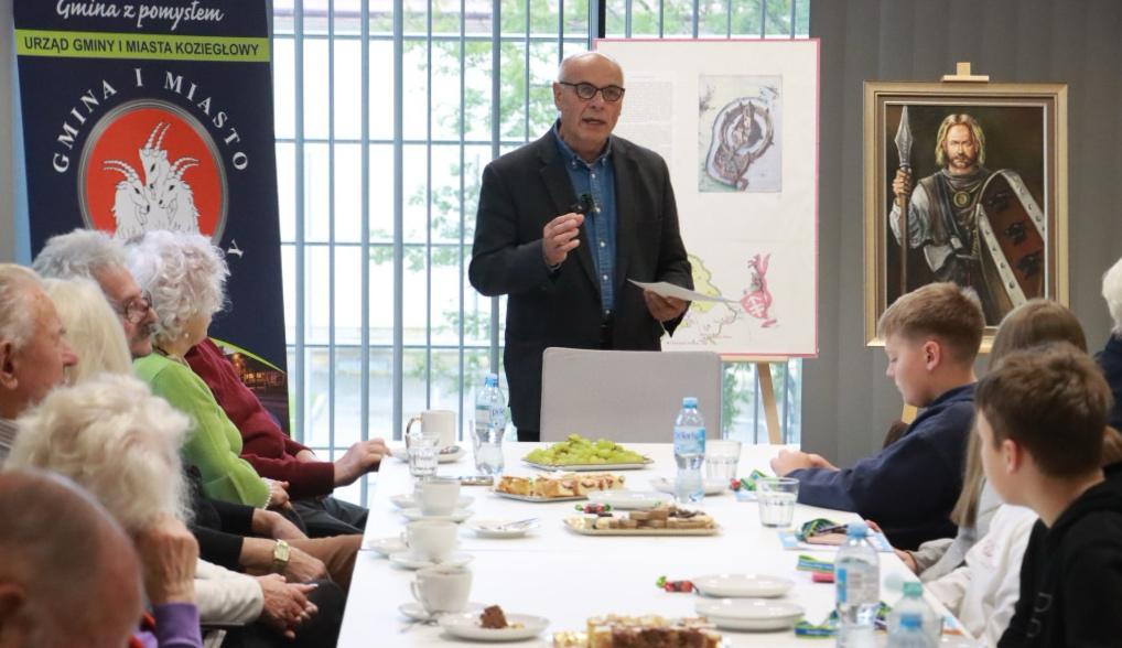 Historyk opowiadający o herbie Koziegłów podczas spotkania przy długim stole